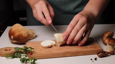 A chef's hands slice a boletus mushroom into pieces with a knife Stock Footage 287571569