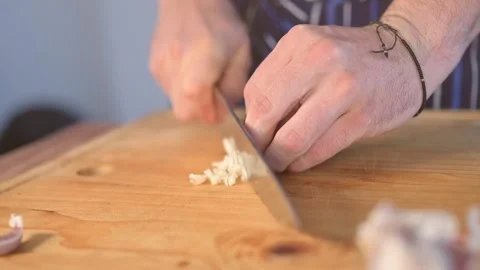 Chef's hands slicing garlic during food preparation in the kitchen Stock Footage 134057525
