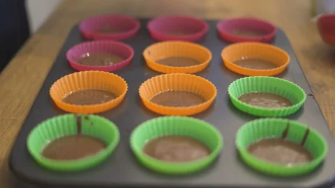 Chef's hands with spoon fill chocolate for baking muffins in paper cups Stock Footage 142138173