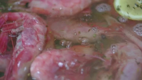Chef's hands throw shrimps into a pan with lemon and garlic. Close-up. HD Stock Footage 141592100