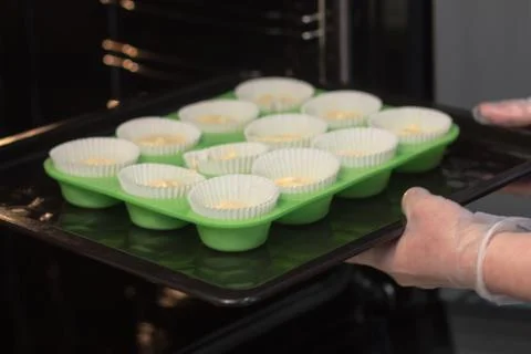 The chef's hands in transparent gloves insert green molds with a cupcakes dou Stock Photos