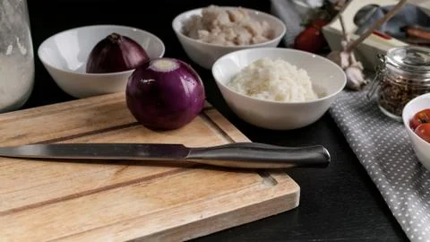 Chef's knife, red onions, cod fish meat, rice, cherry tomatoes and olives. In Stock Photos