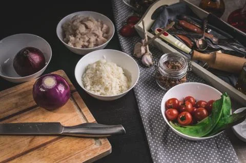 Chef's knife, red onions, cod fish meat, rice, cherry tomatoes and olives. In Stock Photos