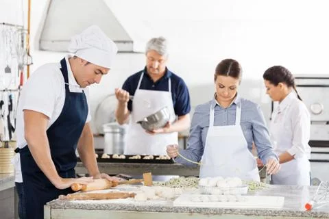 Chefs Making Pasta Together In Kitchen Stock Photos