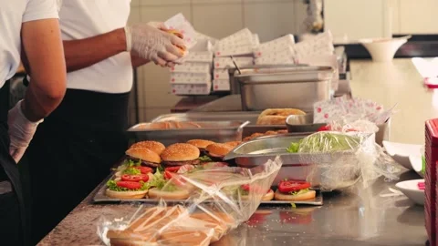 Chefs prepare burgers in an open kitchen for a large group. Charity lunch Stock Footage 332762301
