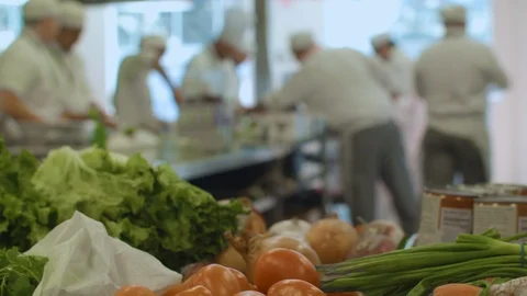 Chefs prepare meals in front of a table filled with vegetables Video stock 91053343
