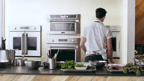 Chefs preparing to cook at their stations in interior kitchen with soft day ligh Stock Footage 199458276