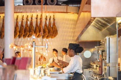 Chefs preparing dishes inside open restaurant kitchen Stock Photos