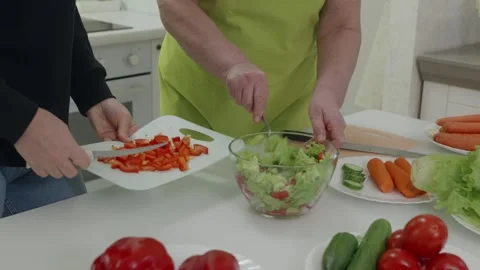 Chefs preparing fresh salad with lettuce, tomatoes, carrots, cucumbers and Stock Footage 312659120