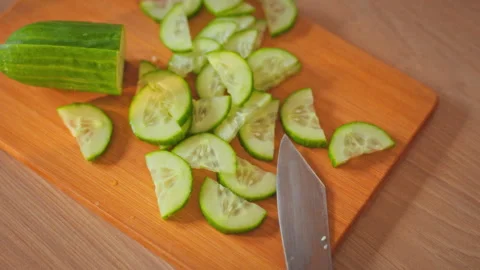 Chefs skilled hands carefully place sliced fresh green cucumber on rustic cu Stock Footage 332480915