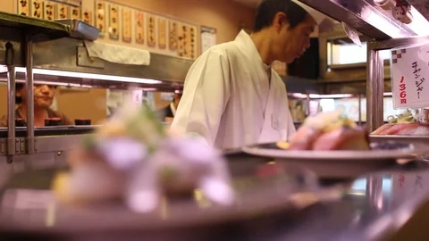 Chefs working in the kitchen and sushi sliding in the tray, Japan Stock Footage 95309548