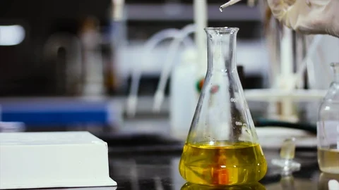 Chemical dropping on a yellow colored liquid in a conical flask and changing  Stock Footage 108711449