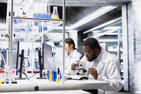 Chemical engineer operating compound microscope, doing sample observation Stock Photos