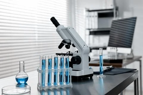 Chemical glassware and microscope on table in laboratory Stock Photos