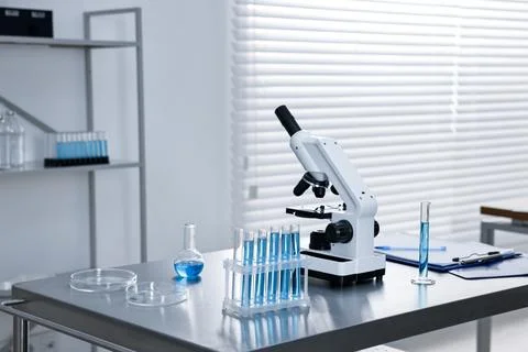 Chemical glassware and microscope on table in laboratory. Space for text Stock Photos