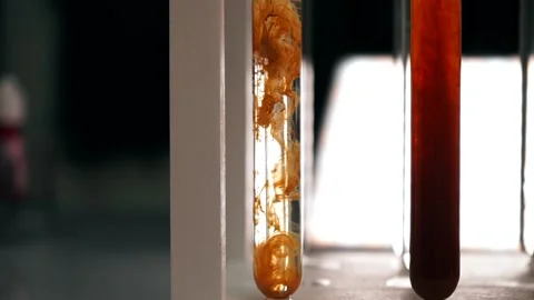 The chemical orange reagent slowly dissolves in a test tube with a clear liquid Stock Footage 188750498