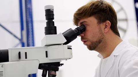 Chemist analysing samples in microscope Video stock 255196168