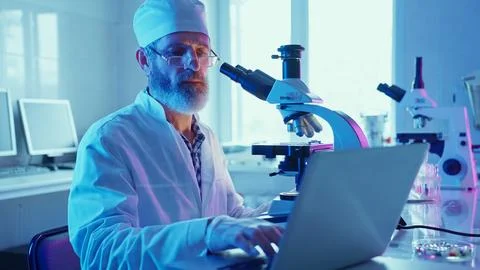Chemist Analyzing Samples Using Microscope in Neon Purple Laboratory Setting Stock Photos