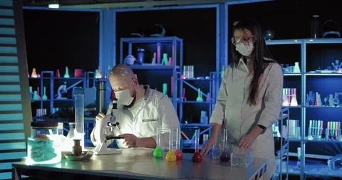 Chemist with an assistant conducting a scientific experiment. Scientist drips a Stock-Footage 104110785