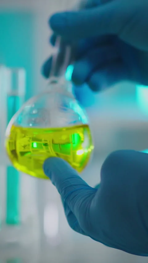 Chemist conducts experiment with yellow liquid in laboratory setting Stock Footage 331537072