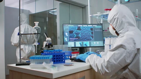 Chemist in coverall typing on computer analysing vaccine evolution Stock Footage 144343345