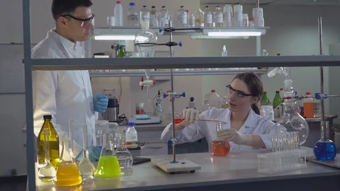 Chemist engineer holding flasks adding liquid to test-tubes with. Stock Footage 113205421