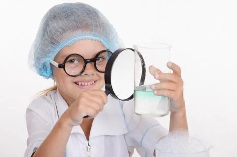 Chemist examines a flask under magnifying glass Stock Photos