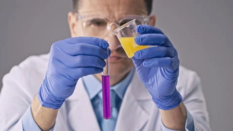Chemist in glasses oversees process of mixing chemicals in test tubes Video stock 130756821