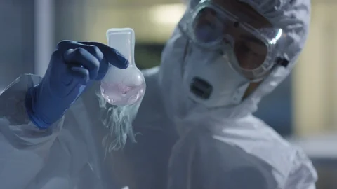 Chemist Holding Flask and Looking at Chemical Reaction Stock Footage 125845342