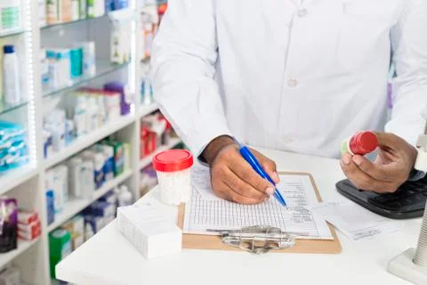 Chemist Holding Pill Bottle While Writing On Paper Foto stock