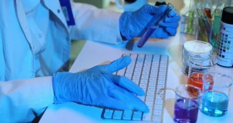 Chemist holds test tube with sample typing data on keyboard Stock Footage 272910607