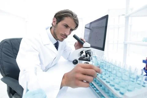 Chemist looking at test-tubes with blue liquids Stock Photos