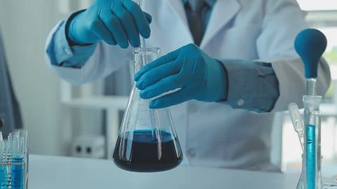 Chemist mixes blue solution in laboratory with scientific equipment Stockbeeldmateriaal 325475377