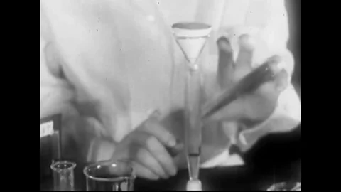A chemist mixes a solution and drips fluid into test tubes in 1930. Stockbeeldmateriaal 143843353