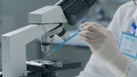 Chemist Pouring Blue Liquid on Microscope Slide in Scientific Laboratory Stock Footage 304765806