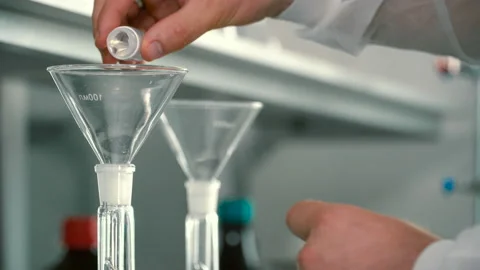 Chemist pouring liquids into a flask through funnel Stock Footage 91440428