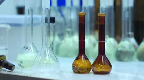 Chemist Pouring Orange Liquid into Flask in Laboratory Stock Footage 11138761