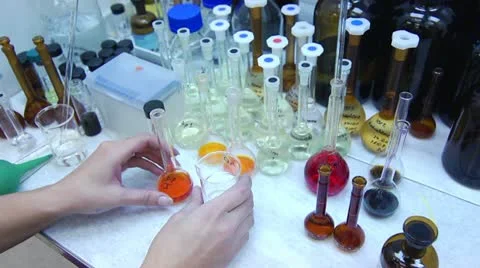 Chemist Pouring Orange Liquid into Flask in Laboratory Stock Footage 11139420