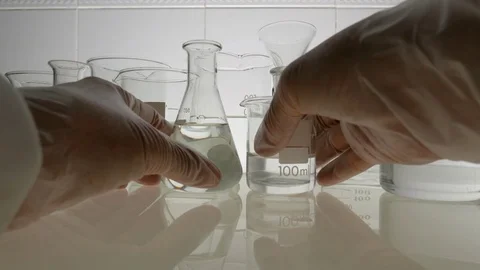 A chemist pours a liquid from a beaker Stock Footage 82072857