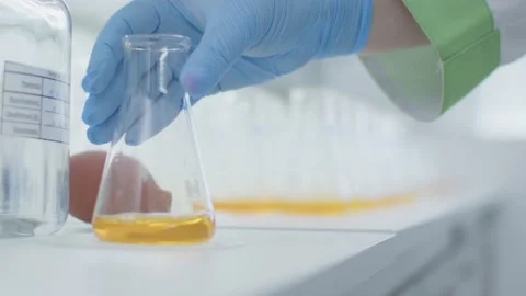 Chemist Puting Laboratory Glass With Yellow Liquid on a Table. Finish experiment Video stock 173173026