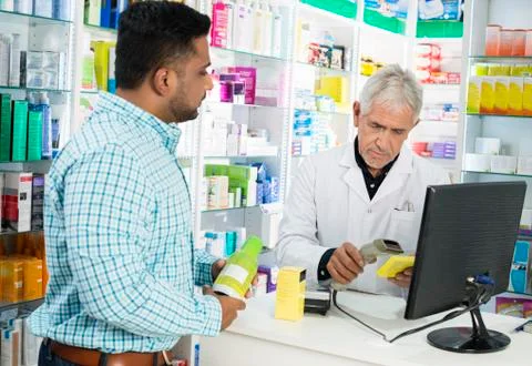 Chemist Scanning Product's Barcode While Customer Standing At Co Stock Photos