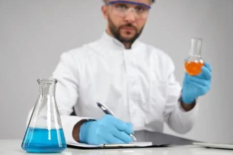 Chemist taking notes while holding flask. Stock Photos
