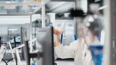 Chemist using laboratory glassware with indicator solution next to coworker Stockbeeldmateriaal 320143236