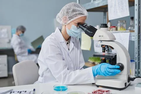 Chemist using microscope at work Photos