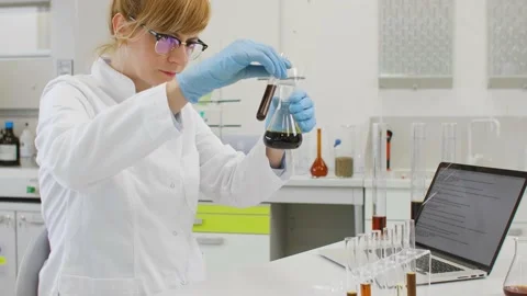 Chemist working with hemp CBD oil in laboratory and writing results in laptop Stock Footage 141913058