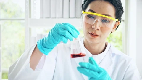 Chemist working in a lab, examine liquid chemical in test flak. Close up shot. Stock Footage 99013748