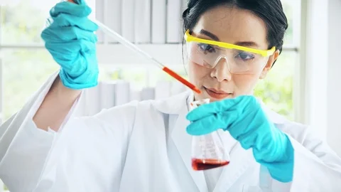 Chemist working in a lab, putting liquid chemical in test flak. Close up shot. Stock Footage 99013750
