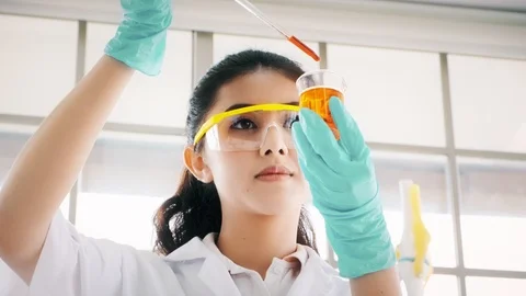 Chemist working in a lab, putting liquid chemical in test tube. Stock Footage 99016369