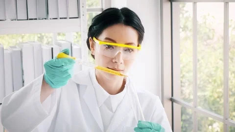 Chemist working in a lab, putting liquid chemical in test tube. Stock Footage 99016376
