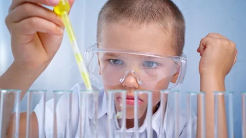 In a chemistry class, a boy was studying the reaction of a liquid. Stock Footage 282593446